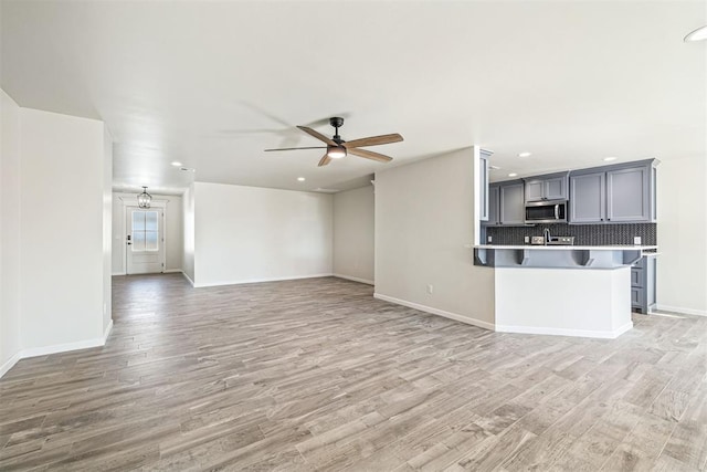 unfurnished living room with ceiling fan and light hardwood / wood-style floors