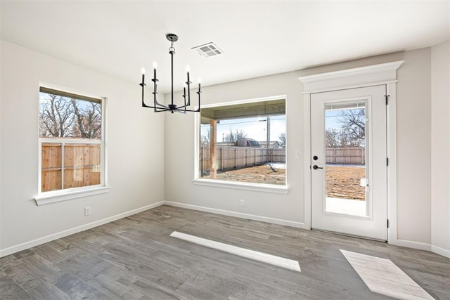 unfurnished dining area featuring a notable chandelier and hardwood / wood-style floors