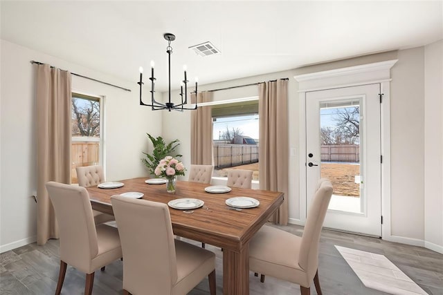 dining area with wood-type flooring and an inviting chandelier