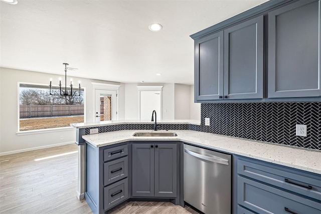 kitchen with decorative light fixtures, backsplash, light hardwood / wood-style floors, stainless steel dishwasher, and sink