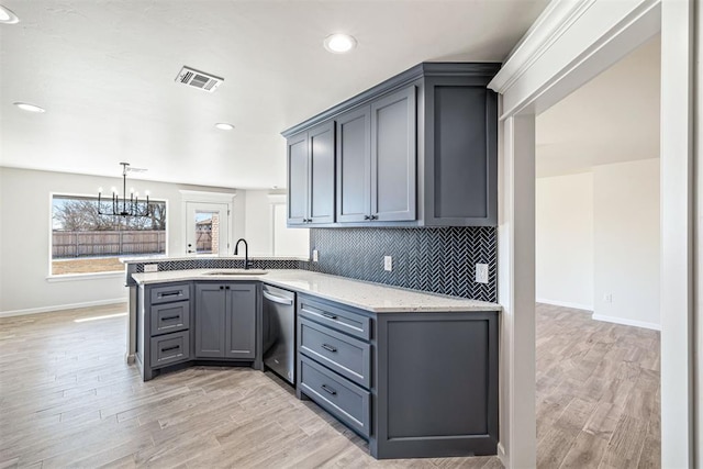 kitchen featuring an inviting chandelier, sink, gray cabinets, stainless steel dishwasher, and light hardwood / wood-style flooring