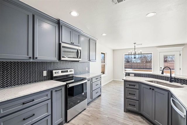 kitchen with stainless steel appliances, gray cabinetry, decorative light fixtures, and sink