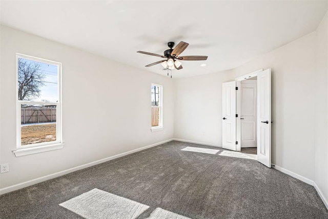 empty room with ceiling fan and dark carpet