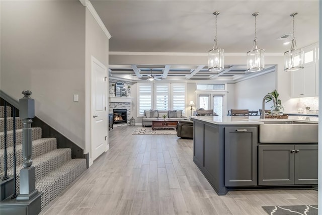 kitchen with beamed ceiling, sink, gray cabinetry, hanging light fixtures, and coffered ceiling