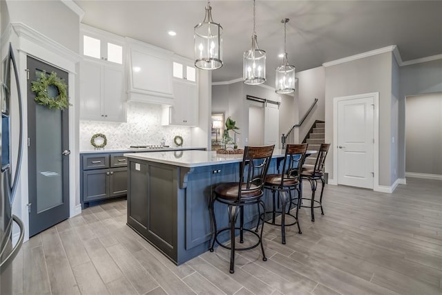 kitchen with a kitchen bar, gray cabinetry, pendant lighting, a barn door, and white cabinets