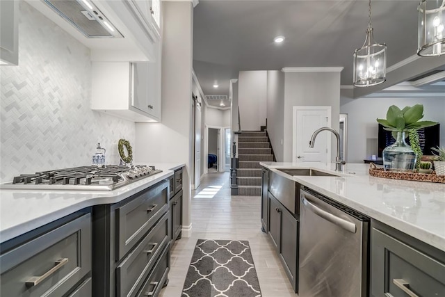 kitchen featuring pendant lighting, stainless steel appliances, light stone countertops, ornamental molding, and a barn door