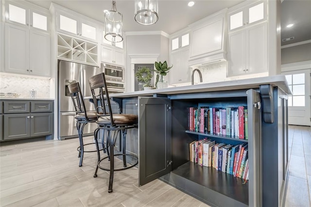 kitchen with crown molding, gray cabinets, stainless steel appliances, white cabinets, and decorative light fixtures