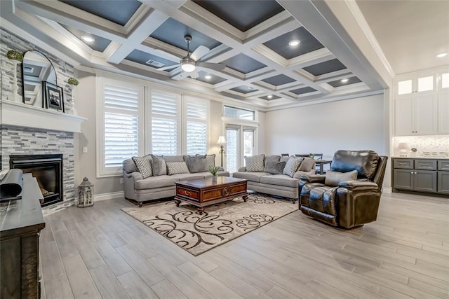 living room featuring coffered ceiling, beam ceiling, ornamental molding, a fireplace, and light hardwood / wood-style floors