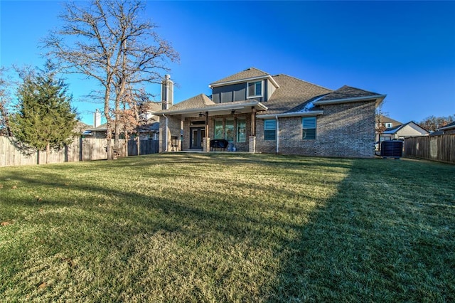 rear view of house featuring cooling unit, ceiling fan, and a lawn