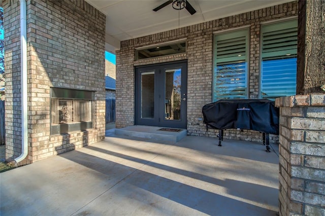 view of exterior entry with ceiling fan, a patio, and an outdoor fireplace