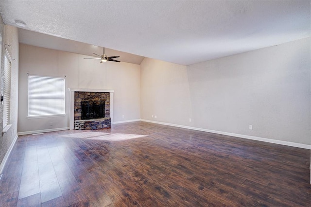 unfurnished living room with vaulted ceiling, dark wood-type flooring, ceiling fan, and a stone fireplace