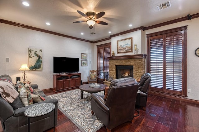 living room featuring ceiling fan, dark wood-type flooring, crown molding, and a fireplace