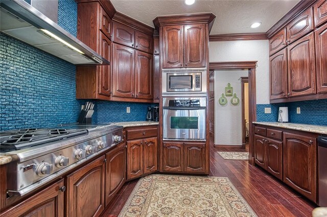 kitchen with appliances with stainless steel finishes, dark hardwood / wood-style flooring, wall chimney range hood, and decorative backsplash