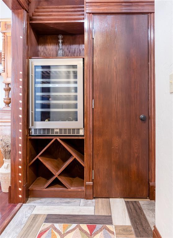 wine room featuring light parquet flooring, bar area, and wine cooler