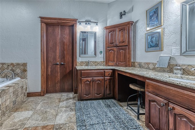 bathroom featuring vanity, tasteful backsplash, and tiled bath