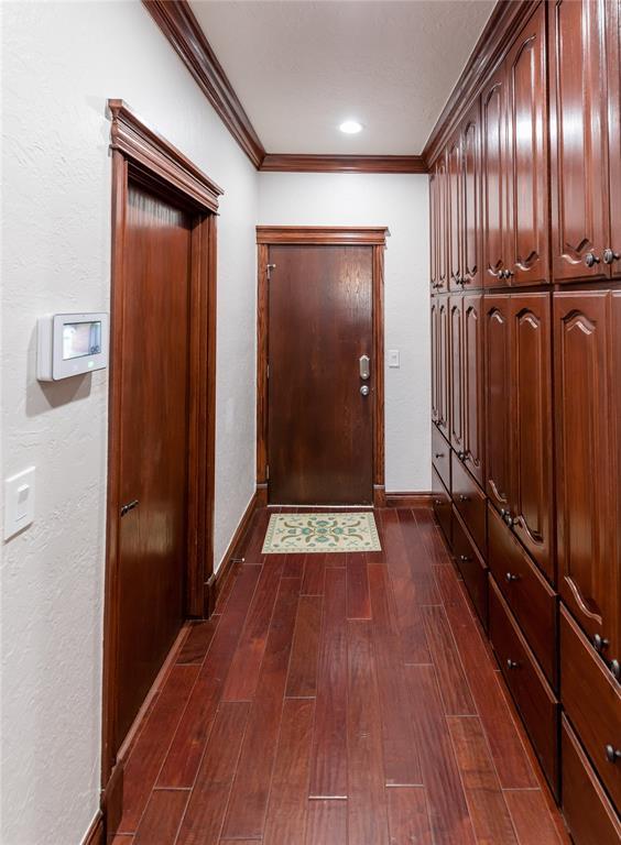 doorway with dark wood-type flooring and crown molding