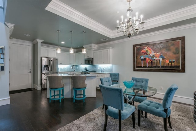 dining space with ornamental molding, a tray ceiling, dark wood-type flooring, sink, and an inviting chandelier