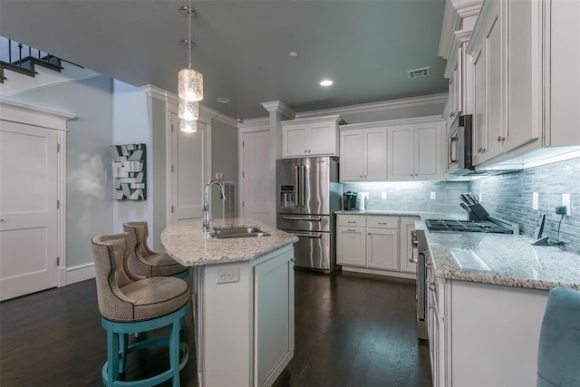 kitchen featuring white cabinetry, sink, decorative light fixtures, a center island with sink, and high end appliances