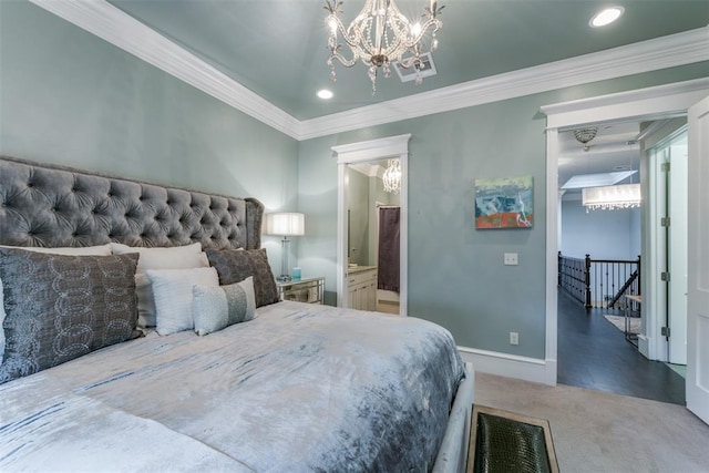 bedroom with carpet flooring, a notable chandelier, ornamental molding, and connected bathroom