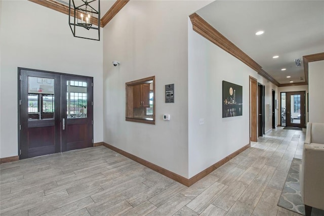 entrance foyer featuring crown molding, french doors, and a chandelier