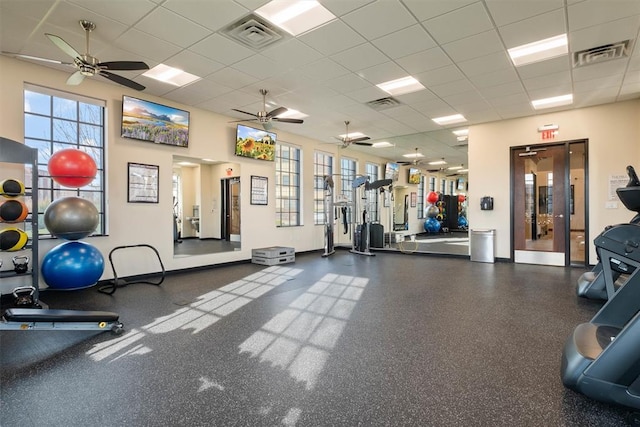 exercise room with a paneled ceiling and a healthy amount of sunlight