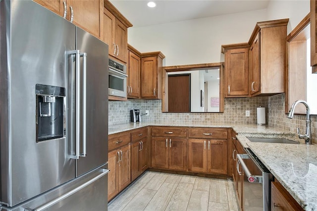 kitchen with sink, light stone countertops, stainless steel appliances, and tasteful backsplash