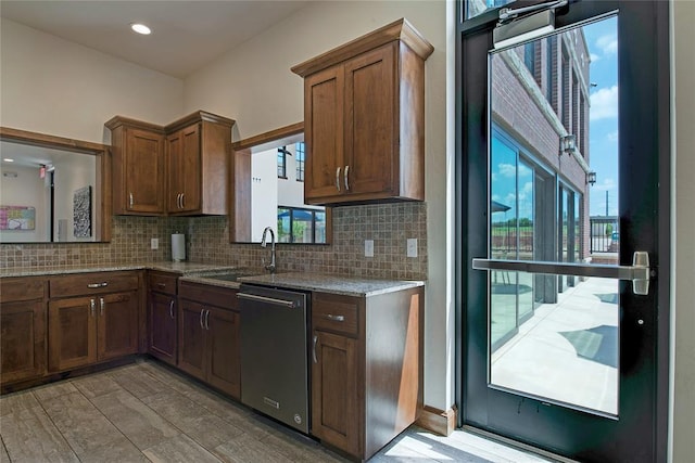 kitchen featuring light stone counters, tasteful backsplash, stainless steel dishwasher, and sink