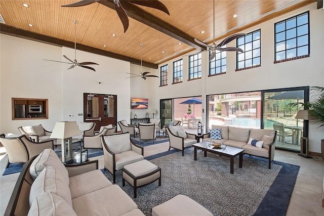 living room with wooden ceiling, a towering ceiling, concrete floors, plenty of natural light, and beam ceiling