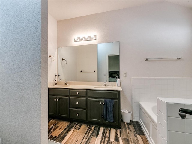 bathroom with a tub to relax in, vanity, and wood-type flooring