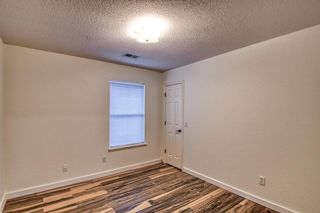 empty room featuring dark hardwood / wood-style floors and a textured ceiling