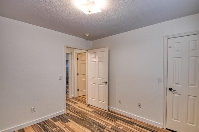 spare room with a textured ceiling and light wood-type flooring