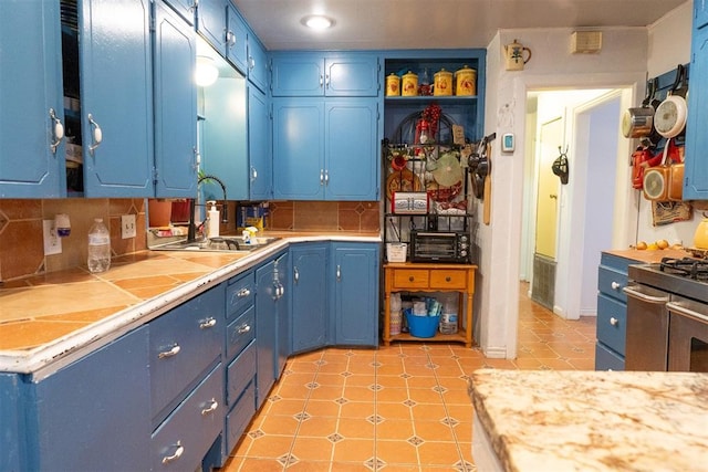 kitchen with blue cabinets, sink, range with two ovens, and backsplash