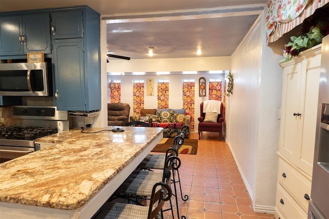 kitchen featuring appliances with stainless steel finishes, a kitchen bar, and light stone countertops