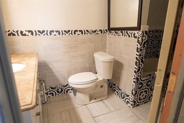 bathroom featuring vanity, tile walls, and toilet