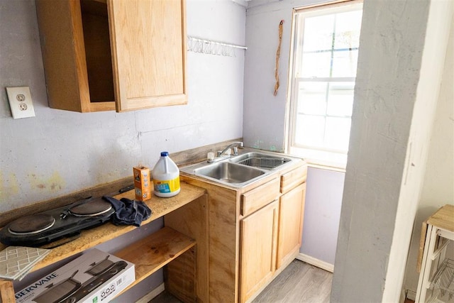 kitchen with light brown cabinetry, sink, and light wood-type flooring