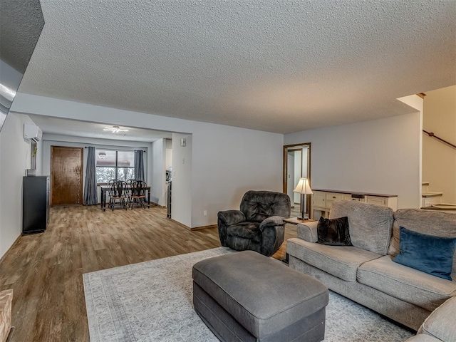 living room with a textured ceiling, a wall mounted AC, and hardwood / wood-style flooring