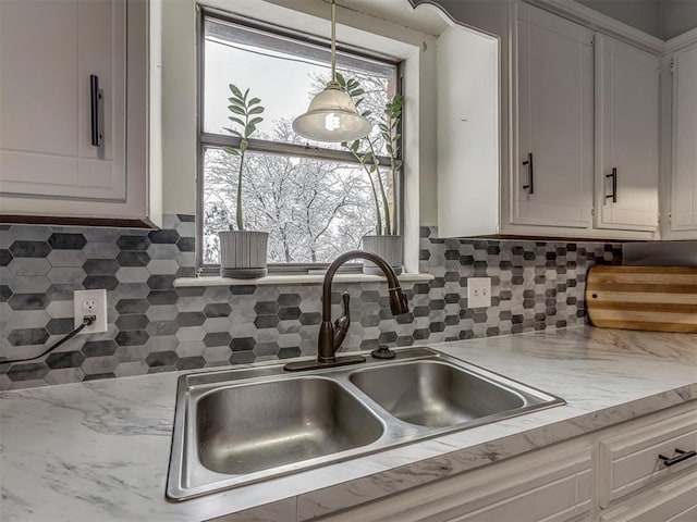 kitchen with sink, a healthy amount of sunlight, white cabinetry, and backsplash