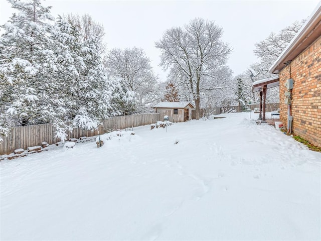 yard layered in snow with a storage unit