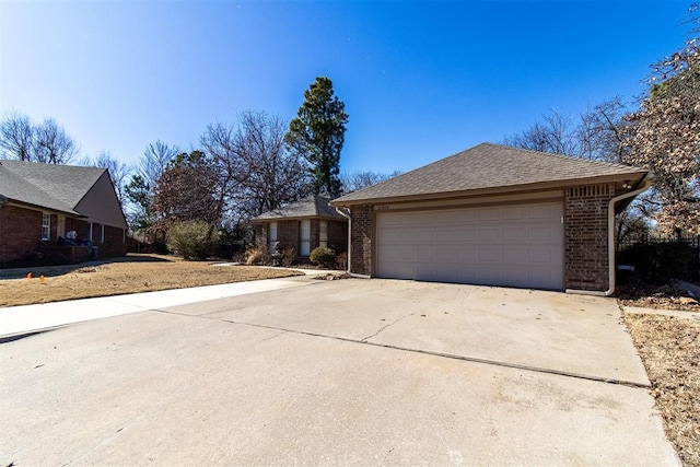 view of front of property featuring a shingled roof, brick siding, and driveway