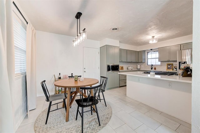 kitchen with stainless steel appliances, decorative backsplash, pendant lighting, and gray cabinets