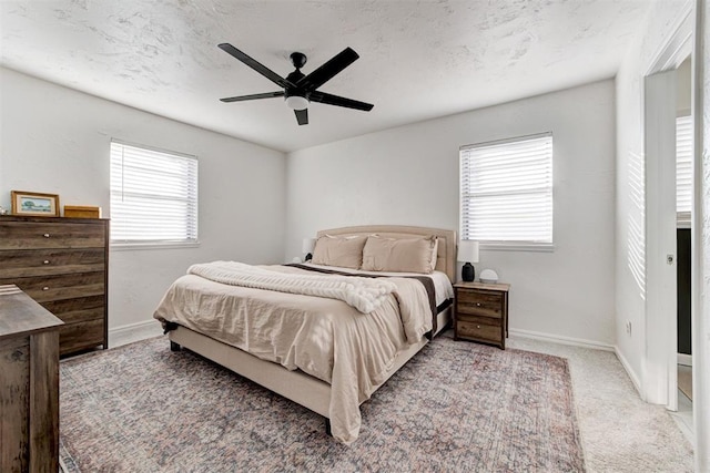 carpeted bedroom with ceiling fan, multiple windows, and a textured ceiling