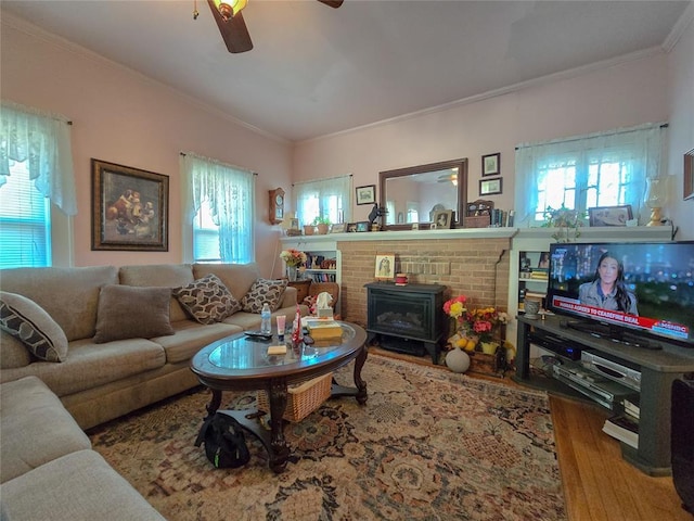 living room featuring ornamental molding, ceiling fan, hardwood / wood-style floors, and a wood stove