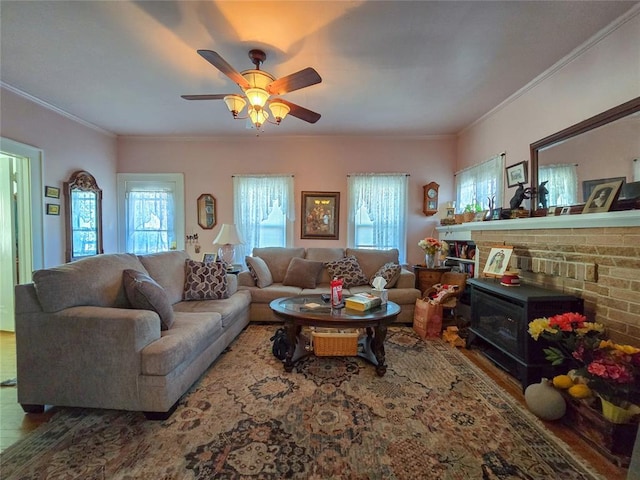 living room featuring hardwood / wood-style flooring, ceiling fan, a wood stove, and crown molding