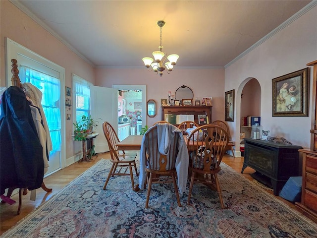 dining area with a chandelier, ornamental molding, light hardwood / wood-style flooring, and a wood stove