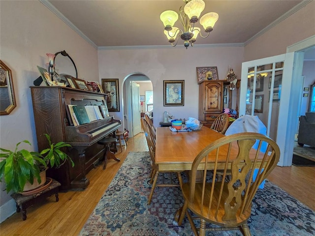 dining space with an inviting chandelier, ornamental molding, and light hardwood / wood-style flooring