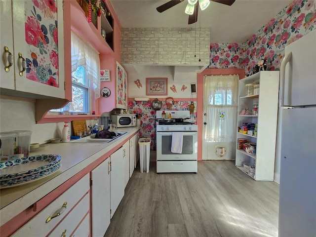 kitchen with white appliances, ceiling fan, sink, light hardwood / wood-style flooring, and white cabinetry