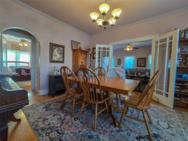 dining area featuring ceiling fan with notable chandelier, ornamental molding, light wood-type flooring, and french doors