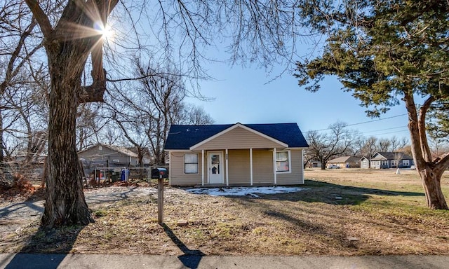 bungalow with covered porch and a front lawn