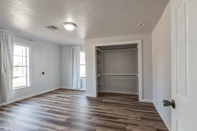 unfurnished bedroom with dark wood-type flooring and a closet