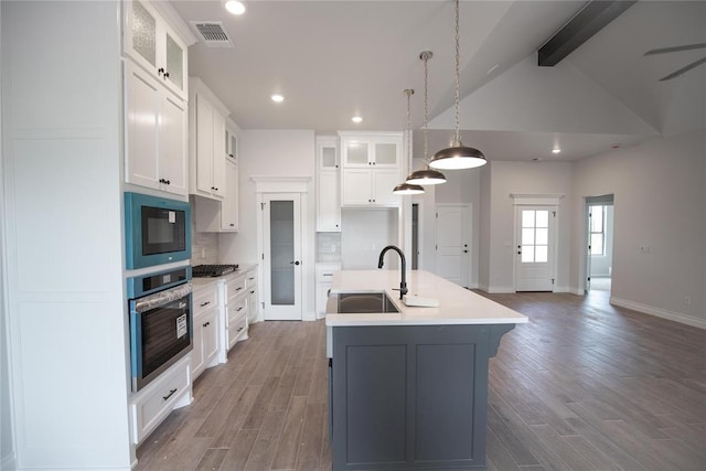 8108 NW 154th St, Edmond, OK 73013 - kitchen with stainless steel appliances, a sink, a kitchen island with sink, tasteful backsplash, and white cabinetry
